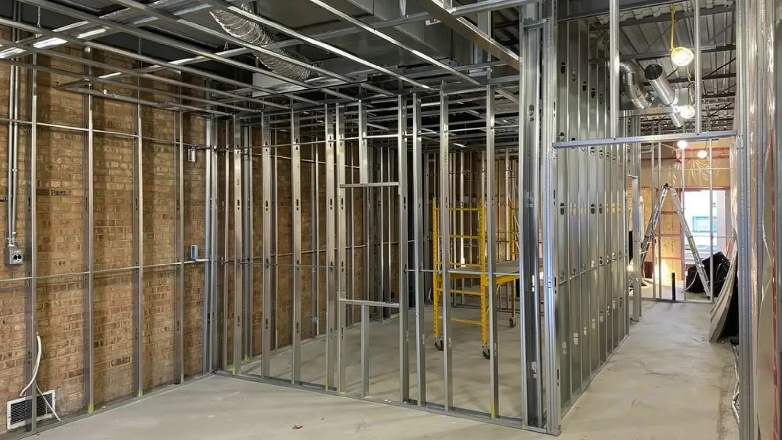 Steel stud partition walls framed inside an unfinished commercial interior, with overhead ceiling framing and ductwork