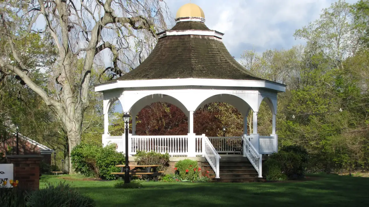 White octagonal gazebo with a gold-domed cupola on the town green lawn in Monroe, Connecticut